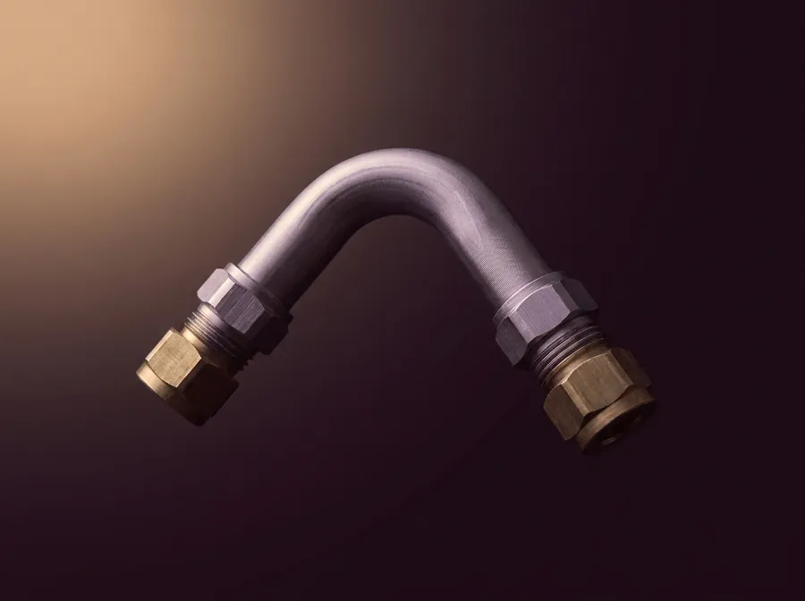 A diesel injector line and its compression fittings, isolated on a dark ground.