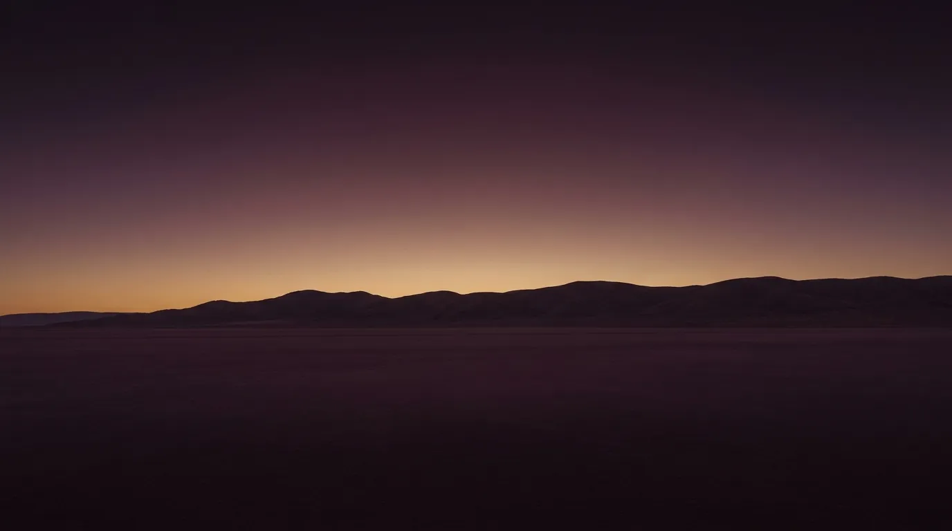 An empty valley horizon at last light, a low ridge running unbroken just below the middle of the frame, under a wide open sky.